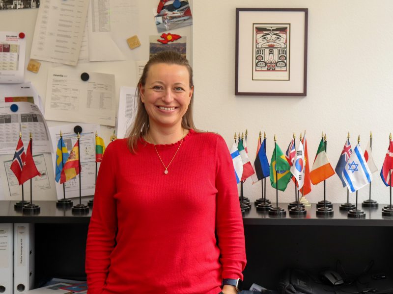 Mirjam Wallimann Koordinatorin im International Office steht in ihrem Büro vor verschiedenen Landesflaggen