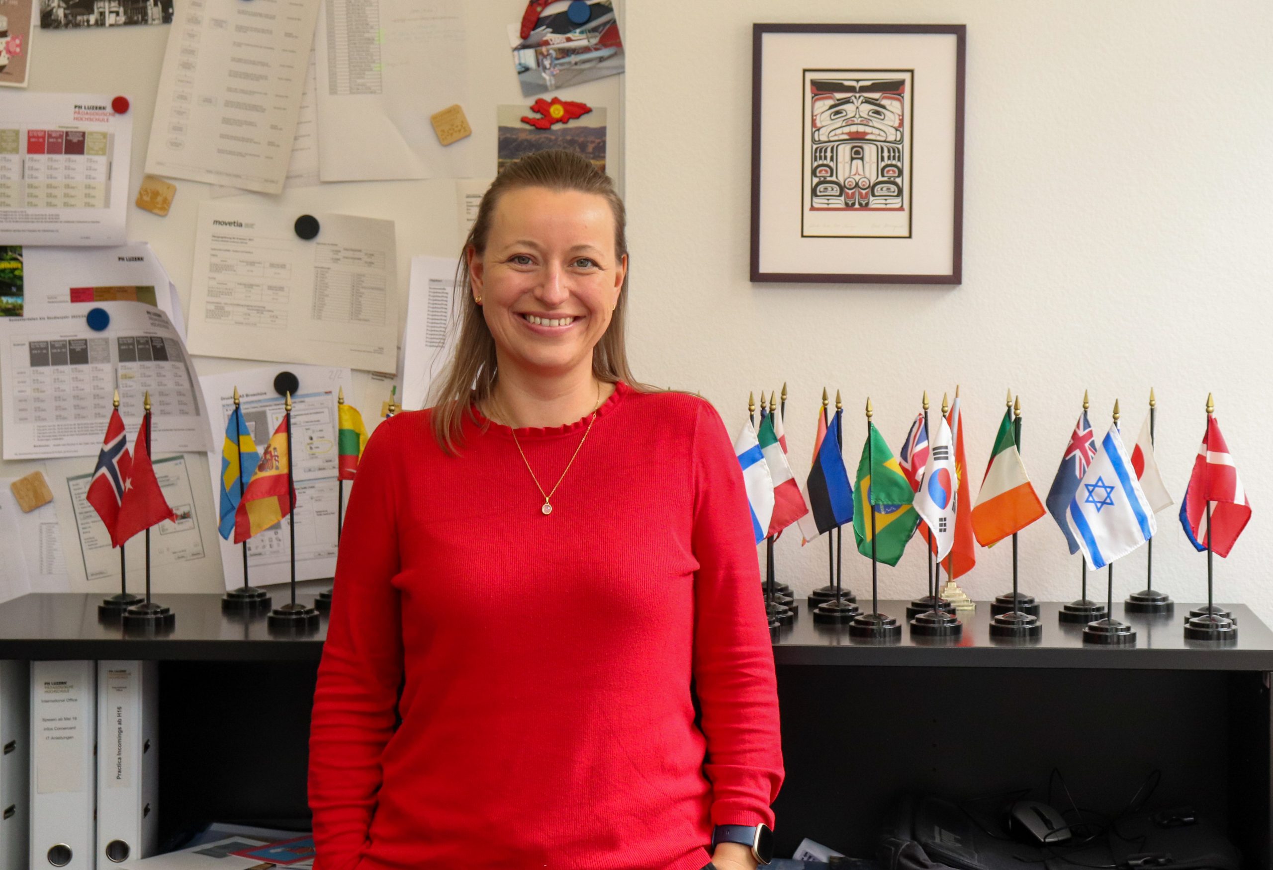 Mirjam Wallimann Koordinatorin im International Office steht in ihrem Büro vor verschiedenen Landesflaggen